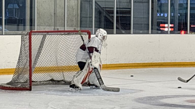 Jonge goalie alleen in de crease tijdens training, focus en concentratie zichtbaar